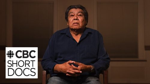 0d9a66b2a0cfdfe977c17faf7a01358b182bc58e An older Indigenous man with his hands clasped sits in a chair, with the CBC Short Docs logo in the bottom left.